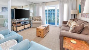 Ein geräumiges Wohnzimmer mit einem Flachbildfernseher, einer Holzkiste und einem Sofa.