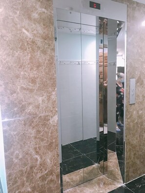 An elevator with a digital display, marble walls, and a tiled floor. - Thanh Vinh Hotel (Ho Chi Minh City)