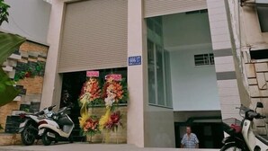 A modern building with a red and grey facade, a closed shuttered entrance, and a sign indicating room number 666/17. - Thanh Vinh Hotel (Ho Chi Minh City)