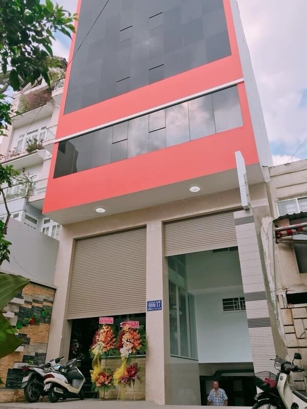 A modern building with a red and grey facade, a closed shuttered entrance, and a sign indicating room number 666/17. - Thanh Vinh Hotel (Ho Chi Minh City)