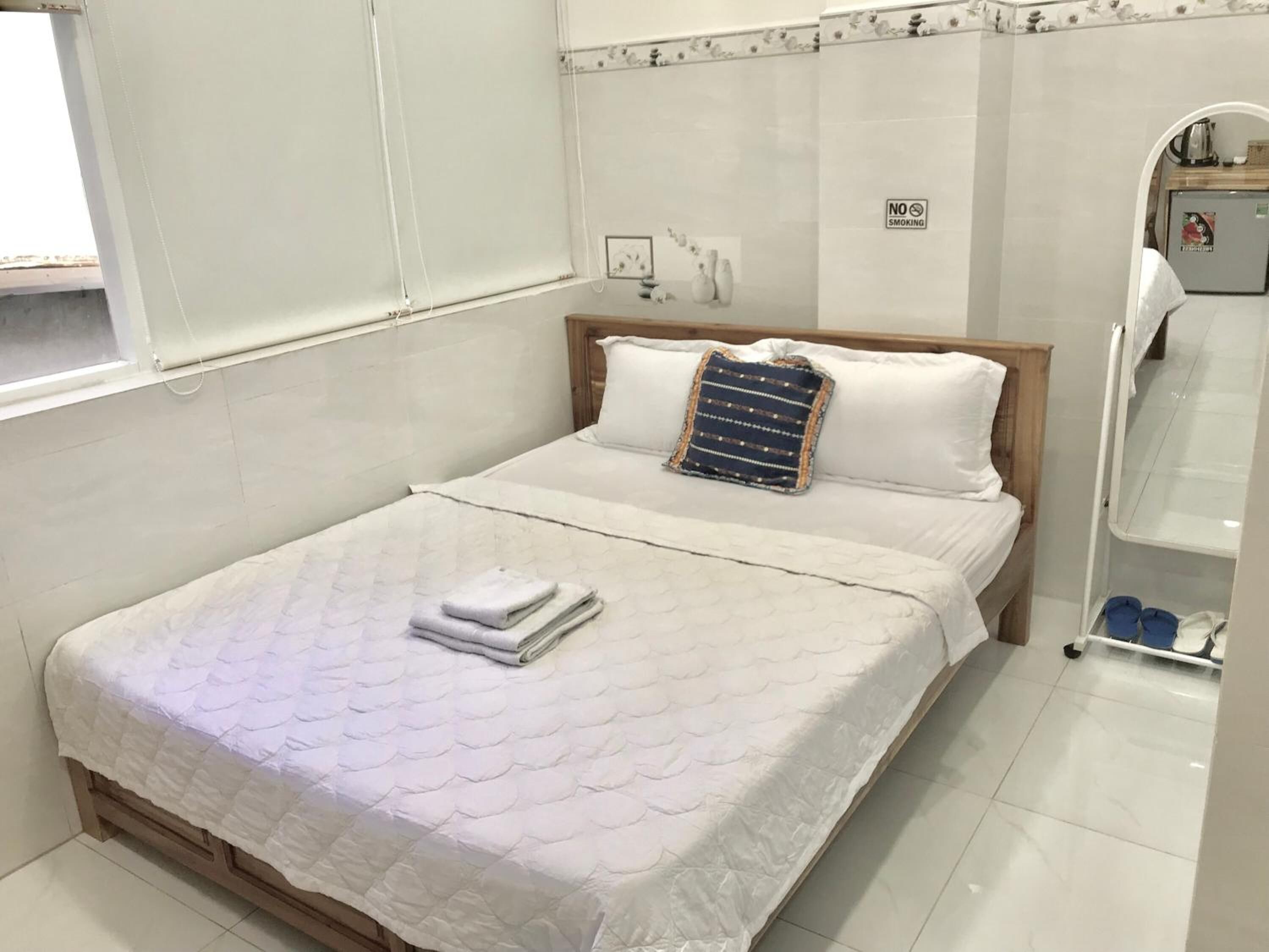 A neatly made bed with a quilted mattress, a folded towel, and a decorative pillow.