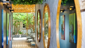 A reception area with a wooden pergola, seating, and artwork on the walls. - Hotel Gondwana - City GREEN (Nouméa)