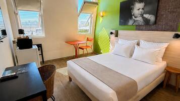 Een hotelkamer met een bed, bureau, stoel, raam en plafondventilator.