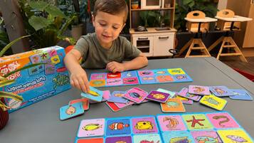 Een kind speelt met een kleurrijk educatief spel met dierenkaarten.