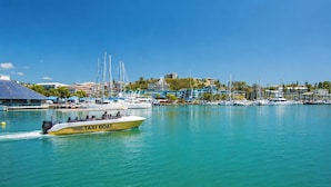 A marina with a yellow taxi boat, several sailboats, and buildings in the background. - Hotel Gondwana - City GREEN (Nouméa)