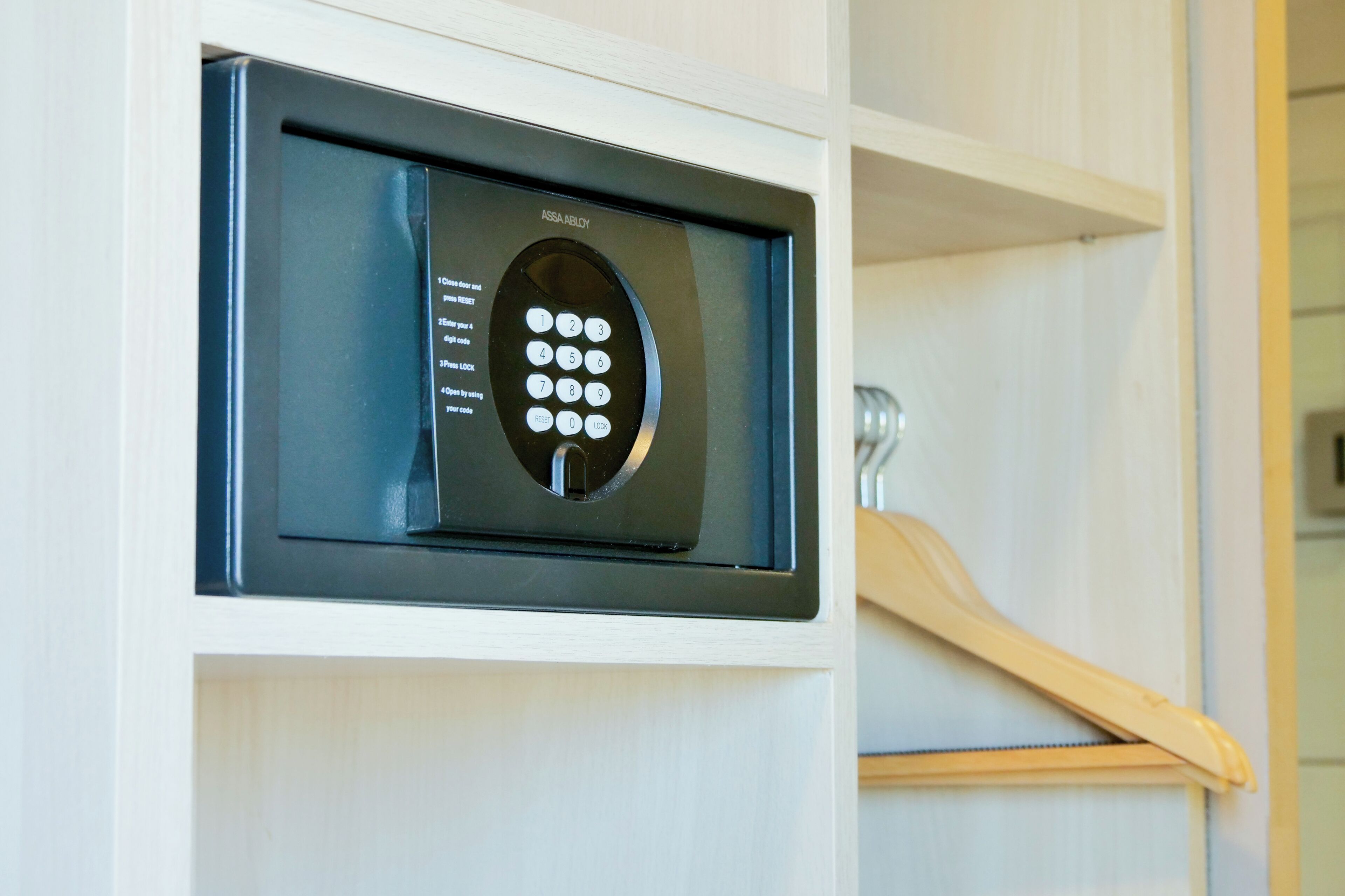 Een keypad slot op een witte deur, een houten kleerhanger en een metalen handgreep.