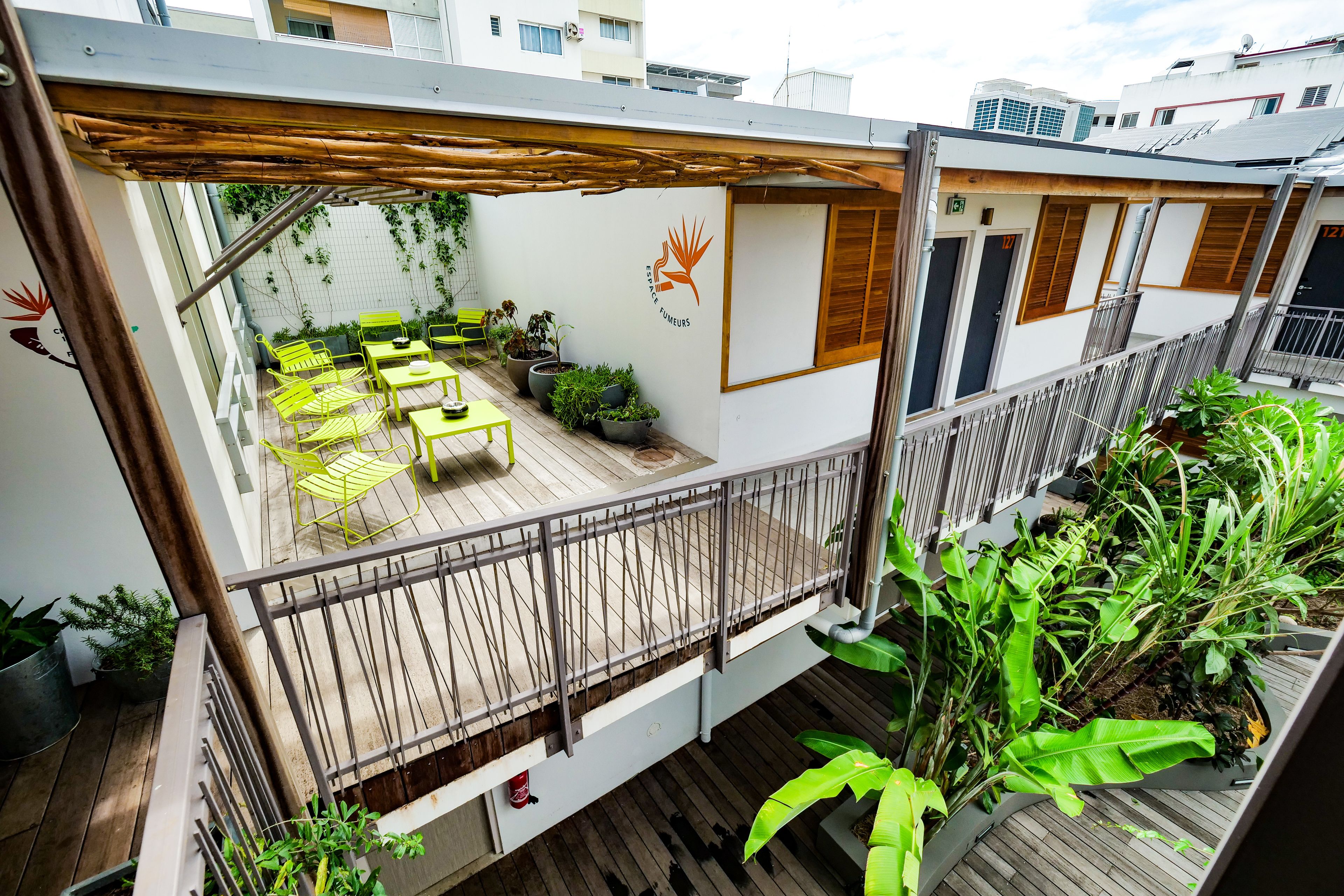 A rooftop terrace with outdoor seating, potted plants, and a wooden deck.