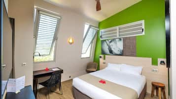 A hotel room with a bed, desk, chair, and a ceiling fan.
