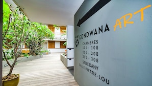 A hotel corridor with a sign listing room numbers and names. - Hotel Gondwana - City GREEN (Nouméa)