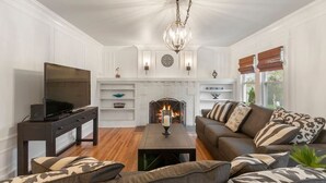 Una sala de estar con televisión, sofá y chimenea.