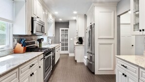 Una cocina moderna con armarios blancos, electrodomésticos de acero inoxidable y encimera de granito.