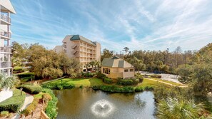 Un hotel con un cortile centrale, un piccolo stagno e vegetazione circostante.