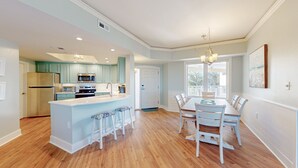 A modern kitchen with a central island, wooden flooring, and a dining area with a chandelier.