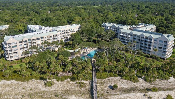 A large resort with multiple buildings, a central pool, and surrounding greenery.