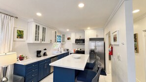 A modern kitchen with white cabinets, a stainless steel refrigerator, and a central island with seating.