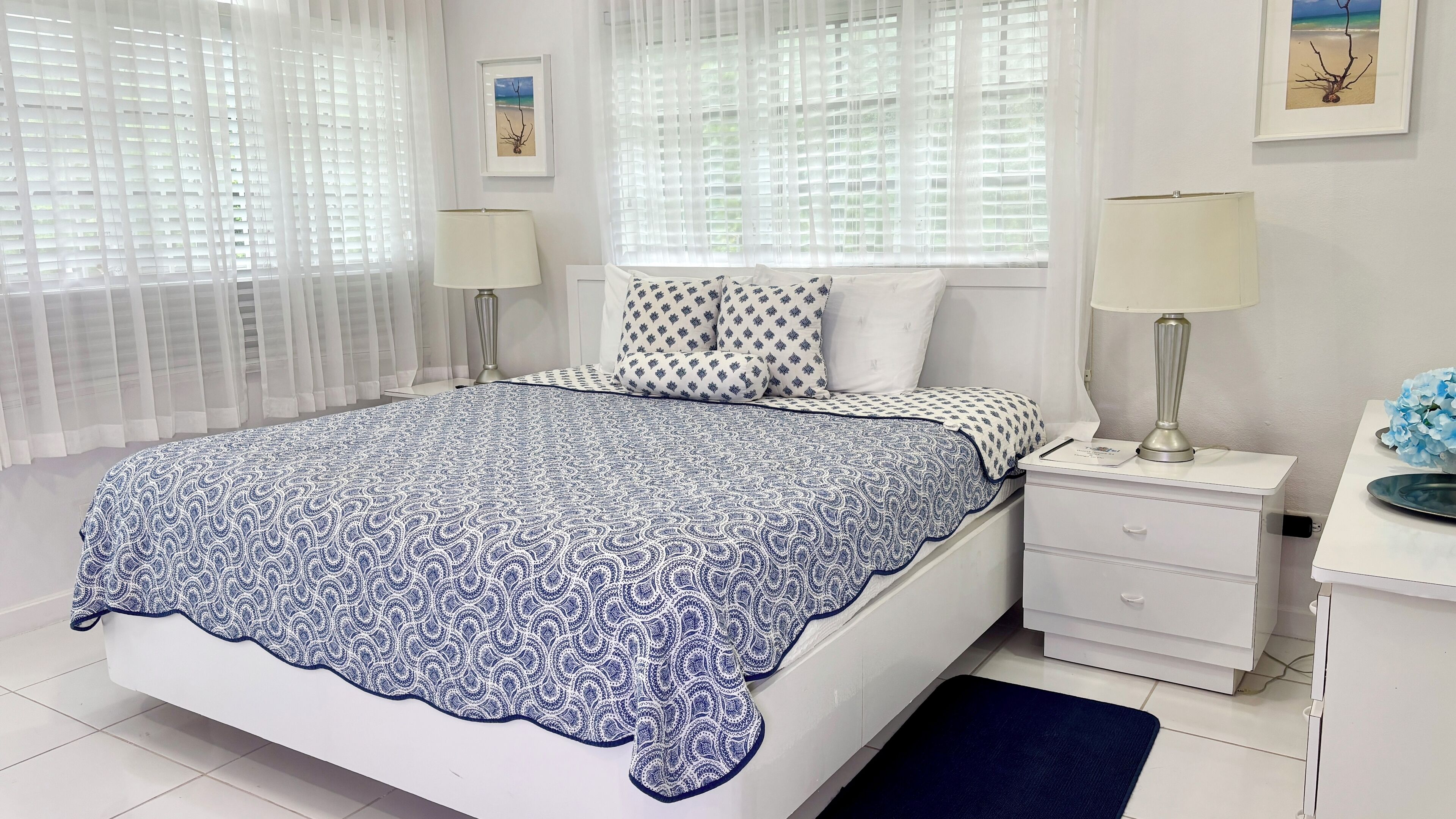 Un dormitorio ordenado con cama, mesitas de noche y escritorio.