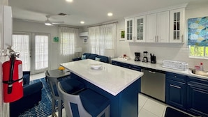 Une cuisine moderne dotée d’un îlot central, de meubles bleu foncé et de plans de travail blancs.