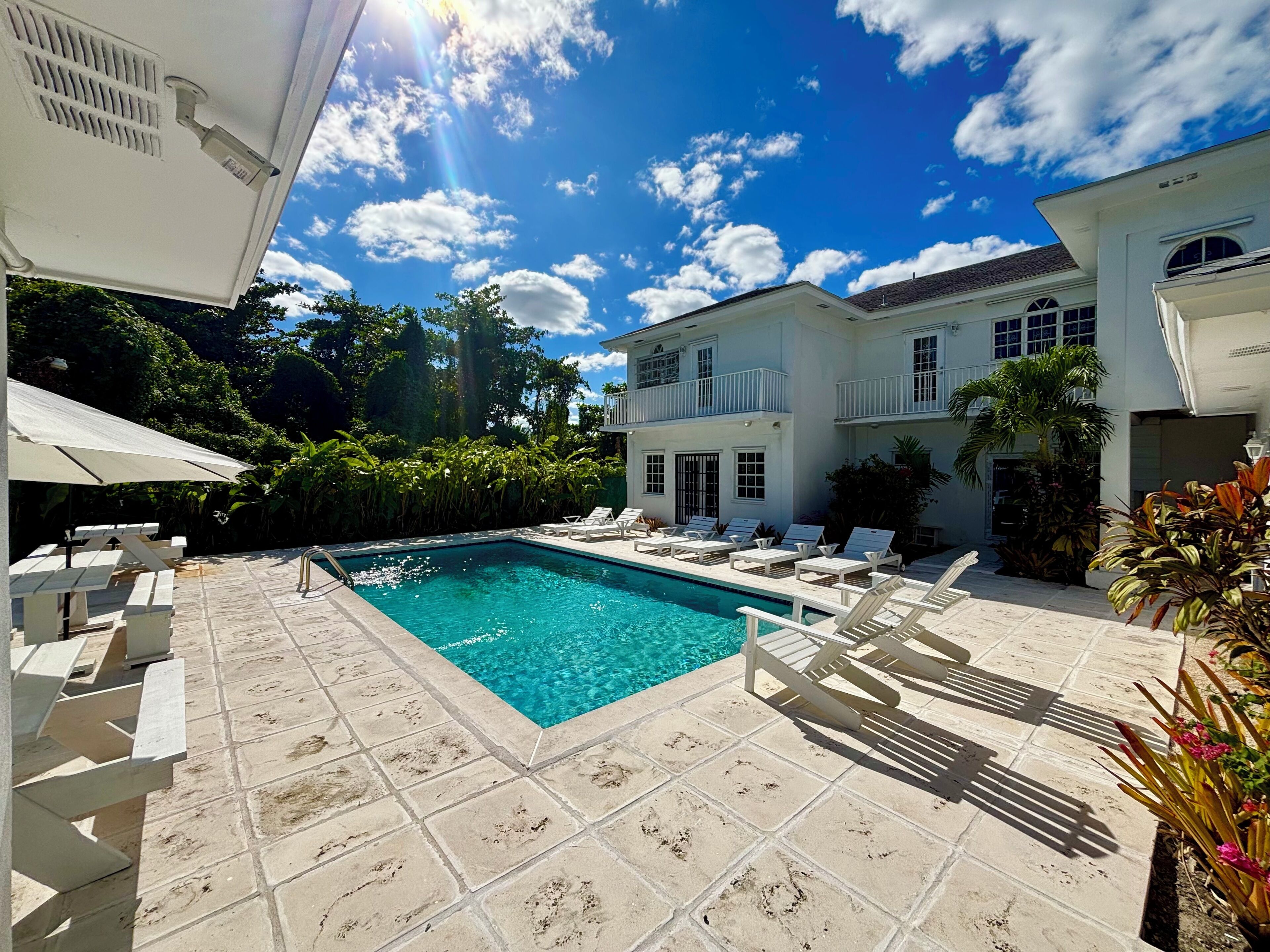 A swimming pool with lounge chairs and a white building in the background.