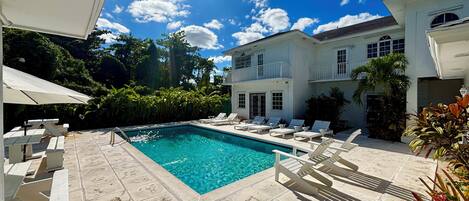 A swimming pool with lounge chairs and a white building in the background.