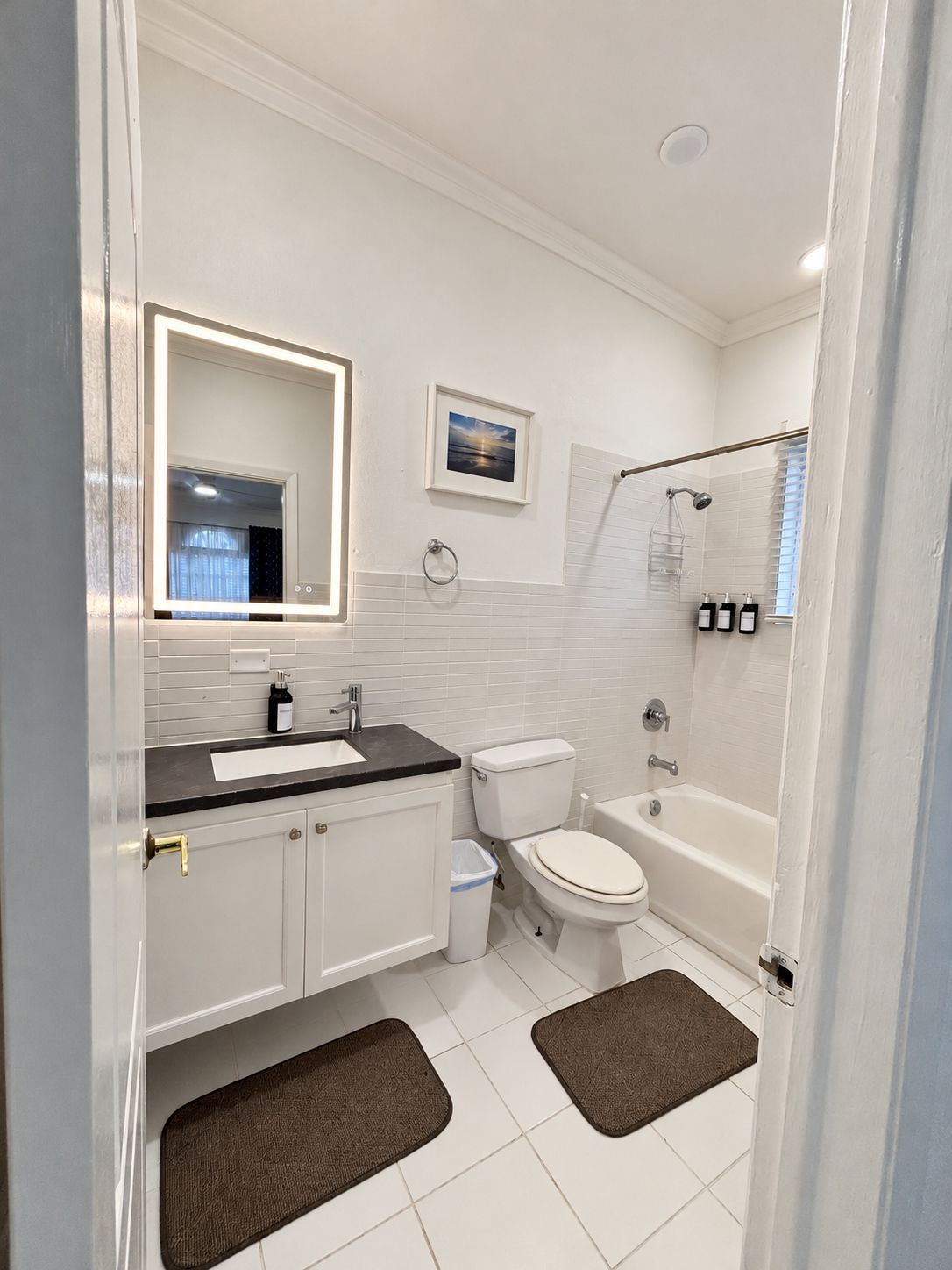 Une salle de bain moderne équipée d’un meuble-lavabo, de toilettes et d’une baignoire.