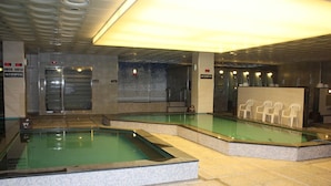Un espace piscine comprenant plusieurs bassins, un comptoir d’accueil et un espace détente avec des sièges.