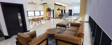 Eine moderne Lobby mit Ledersofas, einem Empfangsbereich und einem großen Fenster, das für natürliches Licht sorgt.
