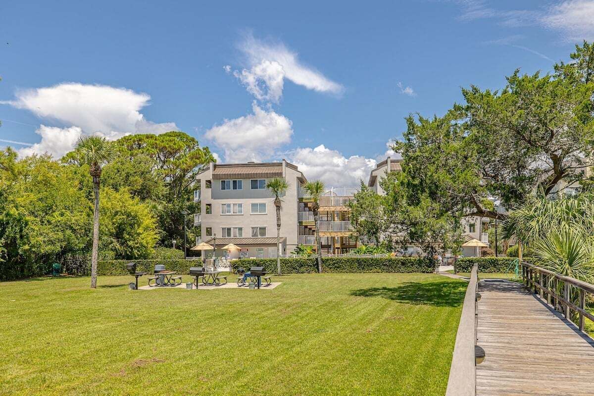 A residential area with a grassy lawn, a wooden deck, and a building with multiple balconies.