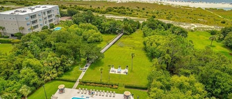 A resort with a swimming pool, lounge area, and a view of the beach and ocean.