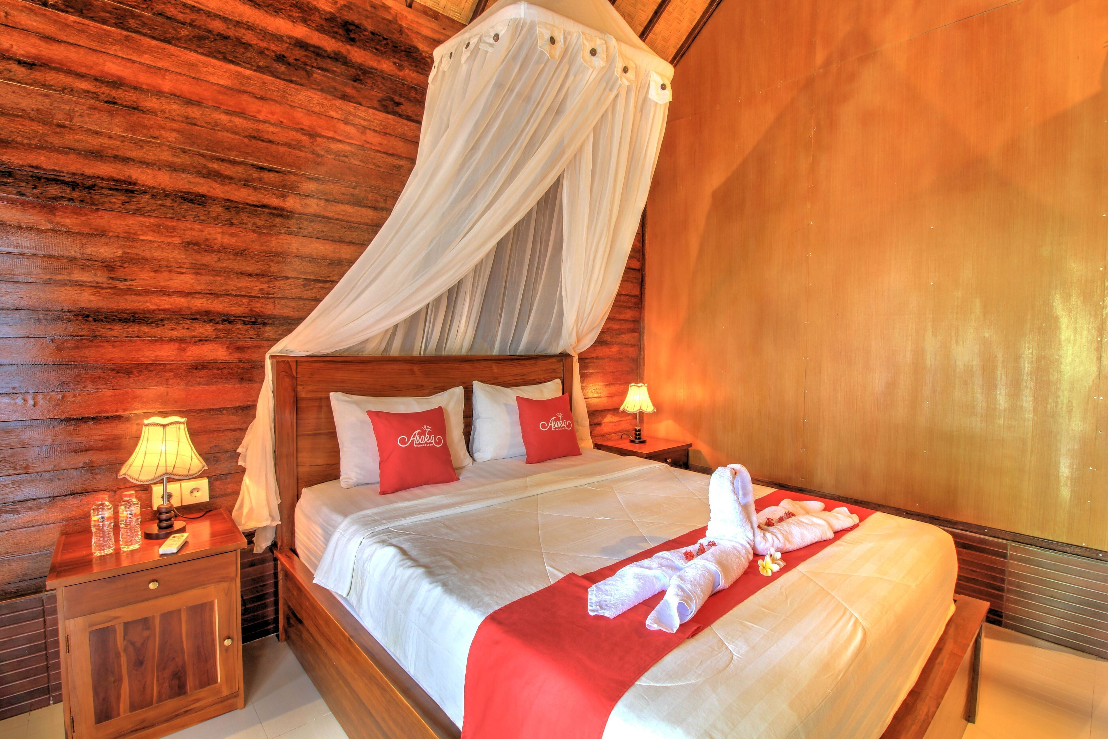 A wooden room with a bed, a nightstand, and a bedside table with a lamp.