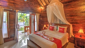 A wooden room with a bed, a nightstand, and a window with curtains. - Asoka Bungalows (Penida Island)