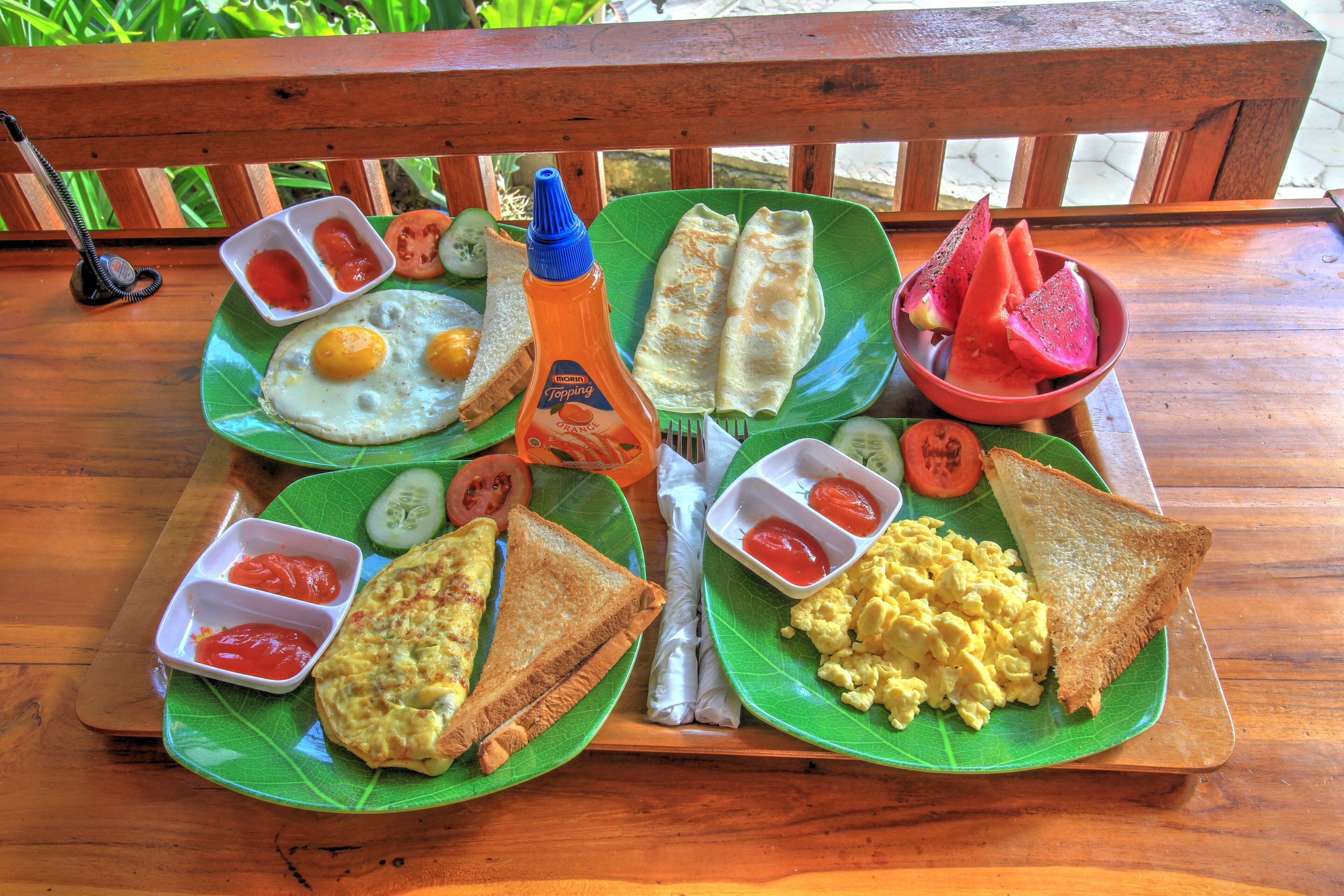 Une table en bois sur laquelle se trouve un plateau contenant divers aliments pour le petit-déjeuner, notamment des œufs, des toasts et une bouteille de sirop.
