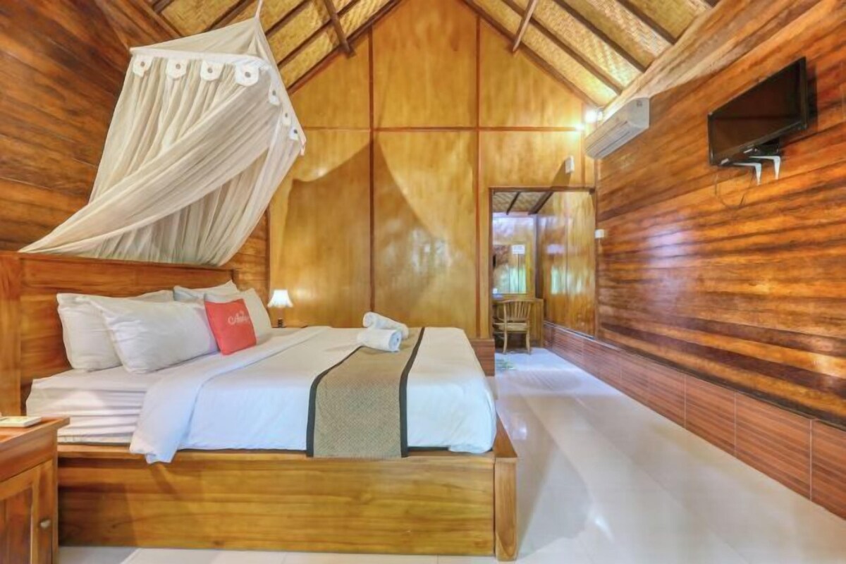 A wooden room with a bed, a canopy, and a TV on the wall.