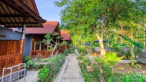 A courtyard with a pathway leading to a wooden building with a red roof. - Asoka Bungalows (Penida Island)