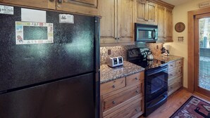 A kitchen with wooden cabinets, a black refrigerator, a microwave, a toaster, and an oven. - Elegant Creekside Condo with Scenic Views & Pool with Access to Grand Hyatt (Vail)