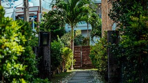 A pathway leading to a gated entrance surrounded by lush greenery and a palm tree. - Sasalamo (Hengchun)