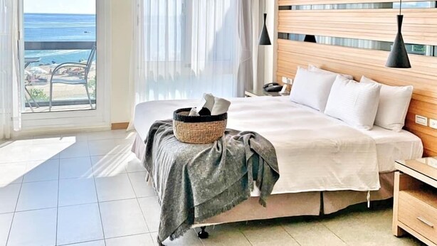 A hotel room with a bed, bedside table, and a view of the beach. - Sasalamo (Hengchun)