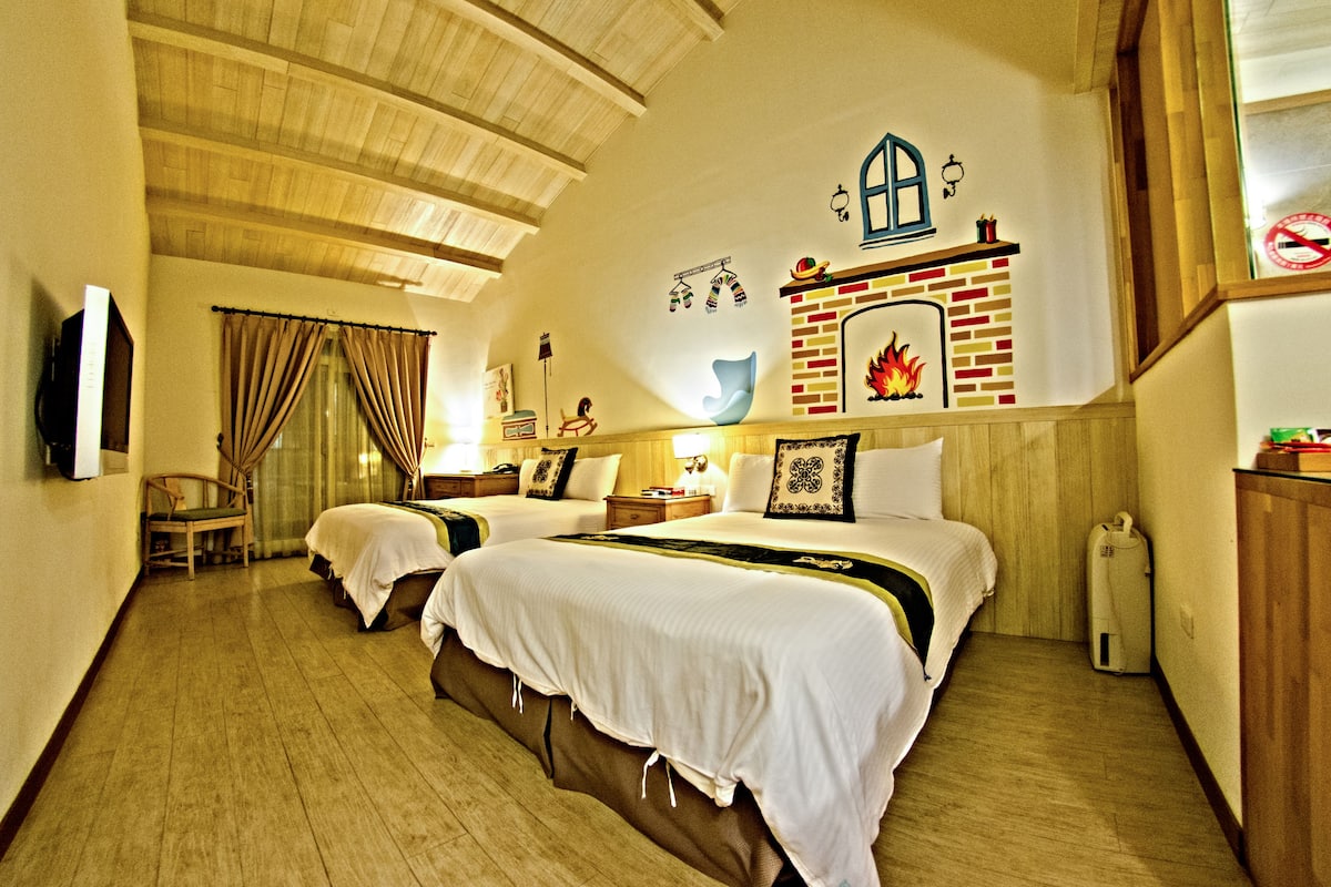 A hotel room with two beds, a fireplace, a television, and a wooden ceiling.