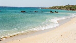A beach with clear turquoise water, sandy shore, and rocky outcrops. - Sasalamo (Hengchun)