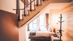 A bedroom with a wooden staircase, a bed with a bedside table, and a wooden headboard. - Sasalamo (Hengchun)
