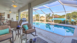 Ein überdachter Außenbereich mit Pool, Sitzgelegenheiten und Deckenventilatoren.
