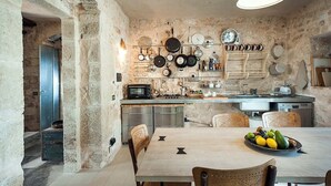 Une cuisine rustique avec des murs en pierre, une table à manger en bois, ainsi que divers ustensiles et appareils de cuisine.
