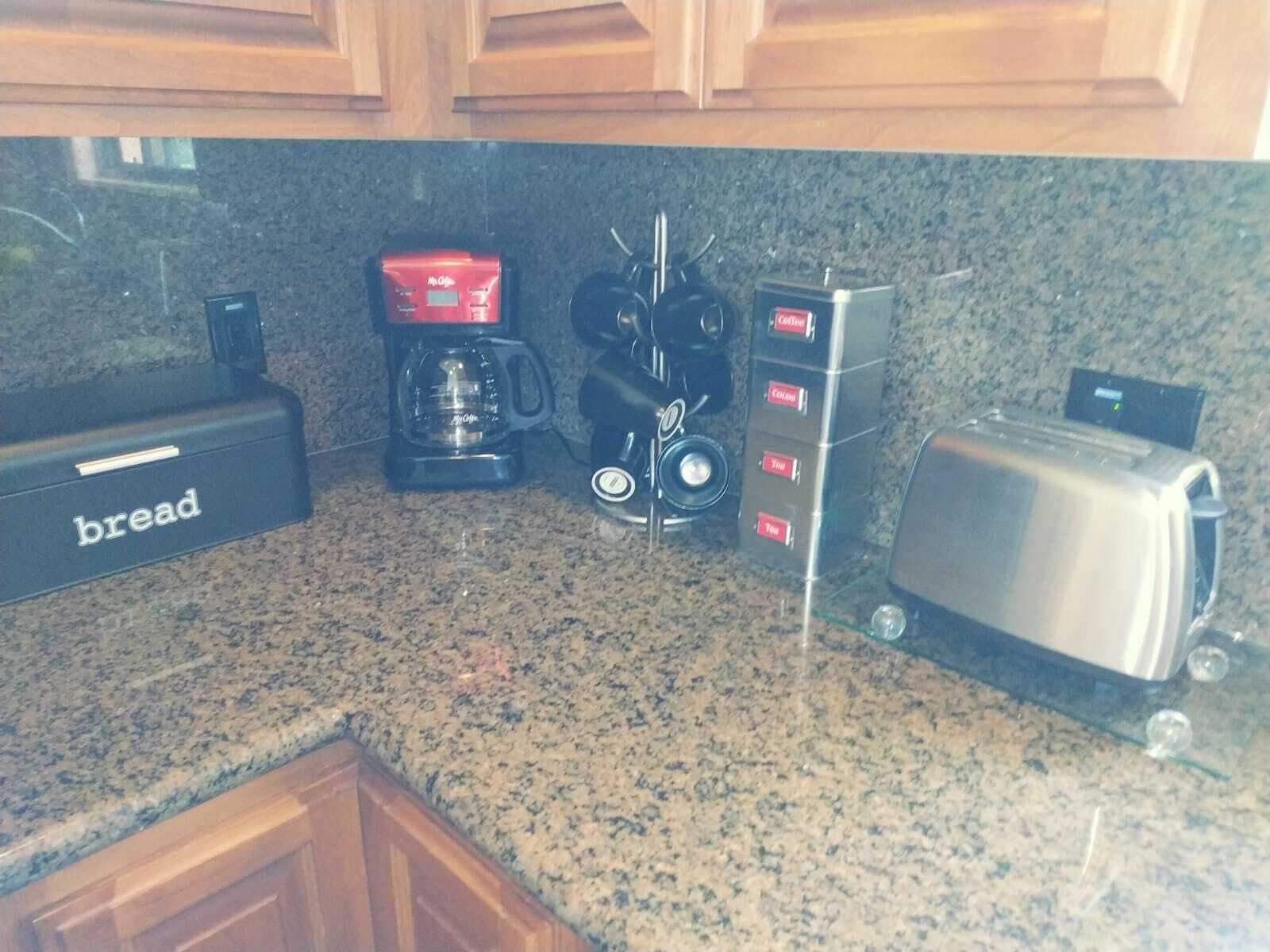 A kitchen with a bread maker, coffee maker, toaster, and a coffee dispenser.