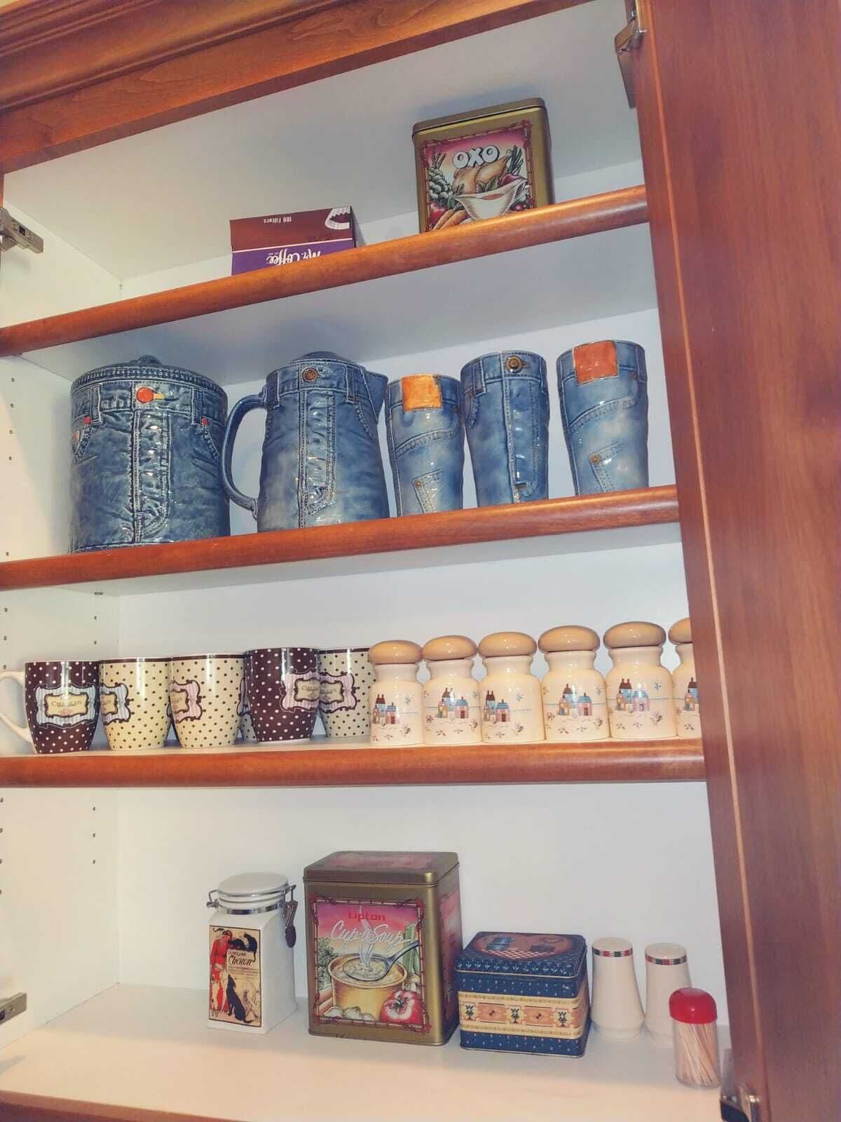 A shelf with denim mugs, ceramic mugs, and kitchenware.