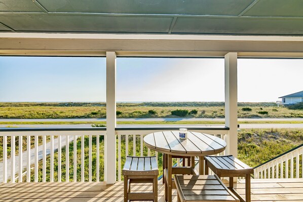 A wooden deck with a table and benches overlooking a grassy landscape. - Panoramic views from the wrap around porch overlooking south bald head (Bald Head Island)