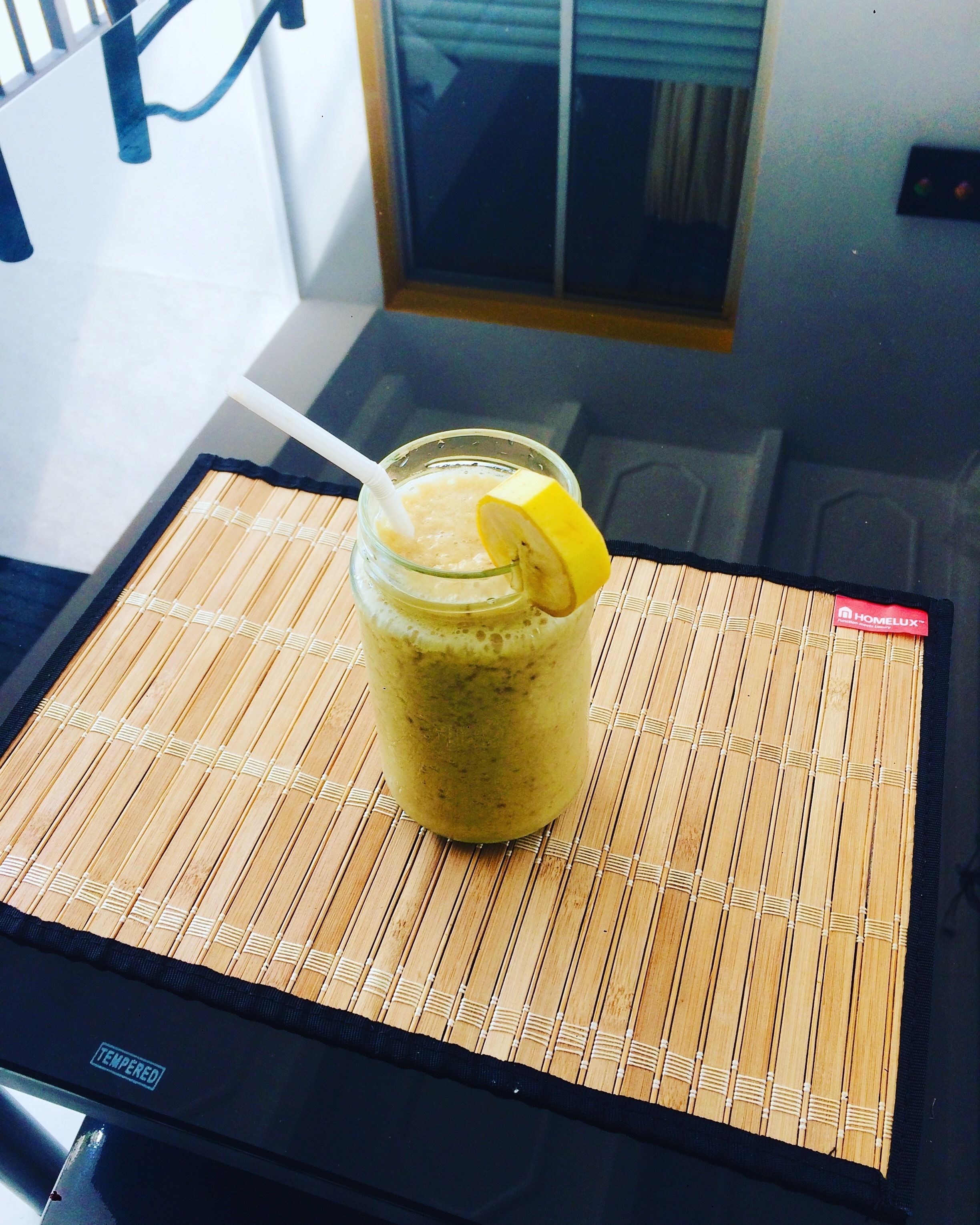 Ein Smoothie mit Zitronenscheibe auf einer Bambusmatte.
