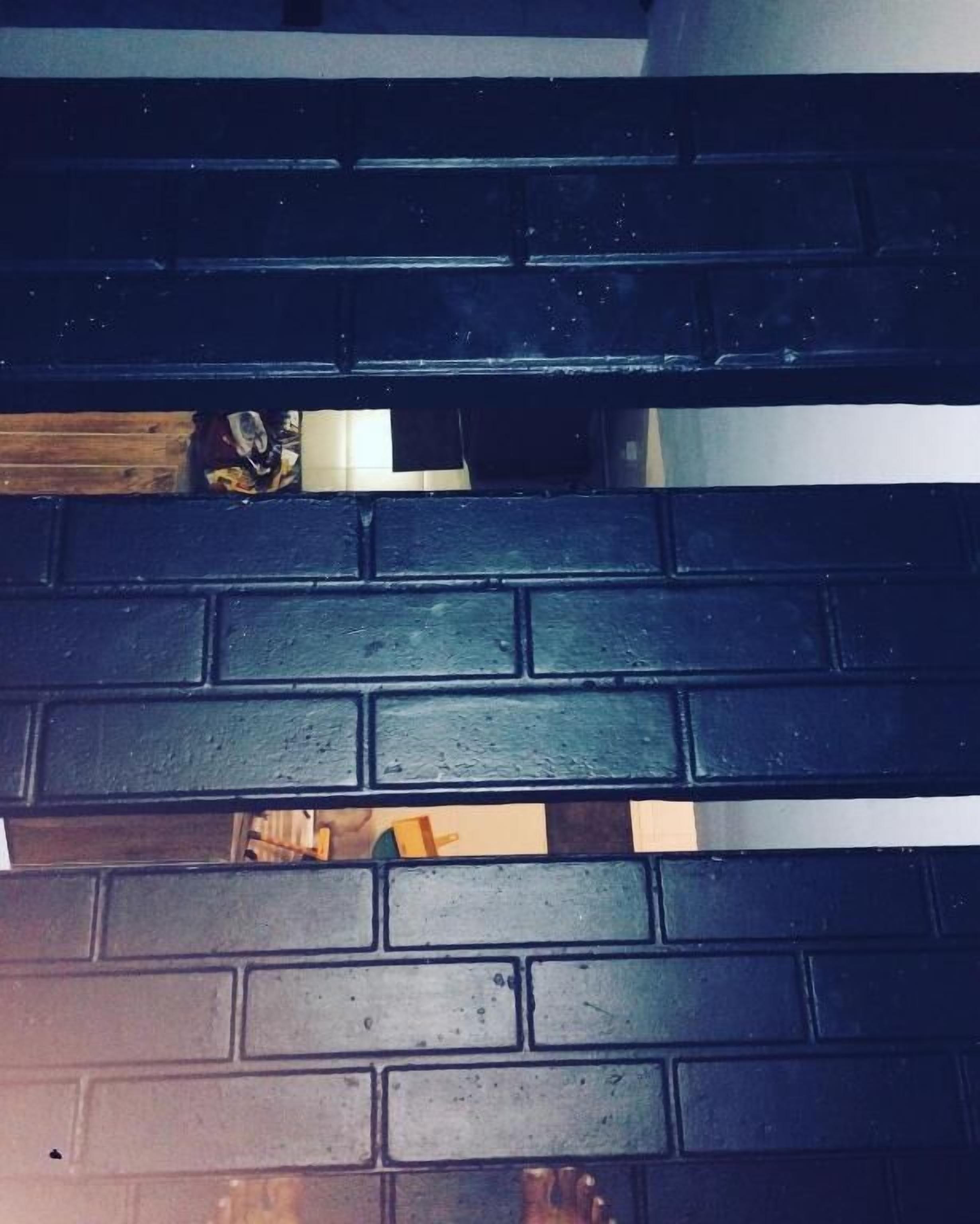 Una pared de ladrillo oscuro con un marco de puerta blanco.