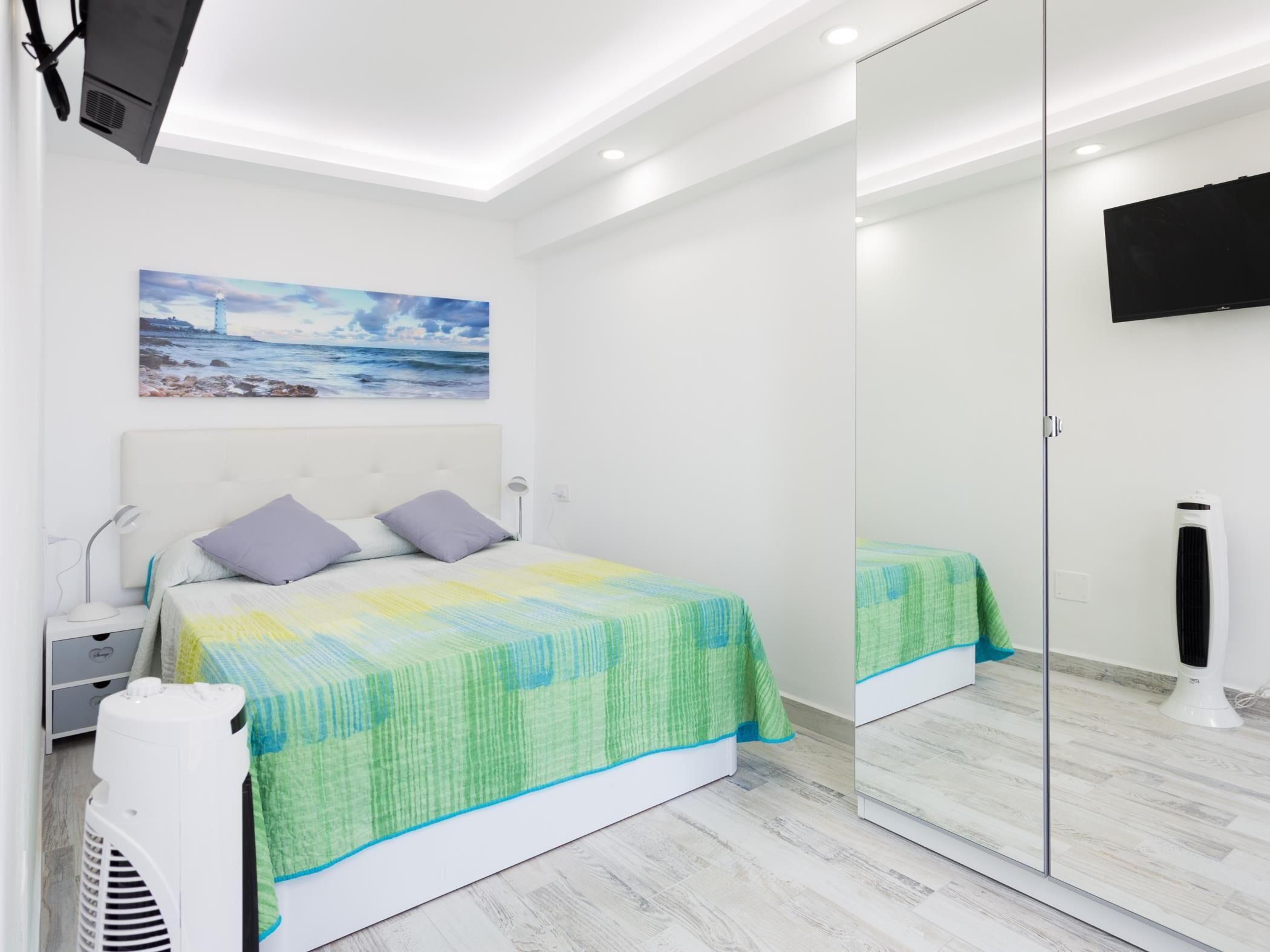Ein Schlafzimmer mit Bett, Nachttisch, Lampe und einem Bild an der Wand.
