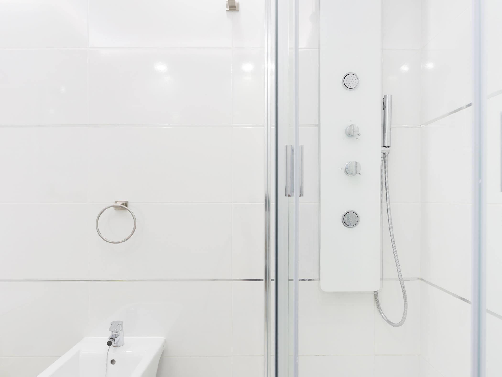 Un baño moderno con cabina de ducha de vidrio, un lavamanos y un porta toallas.
