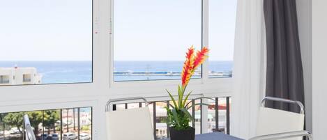 Een hotelkamer met balkon, een tafel met bloevas en uitzicht op zee.