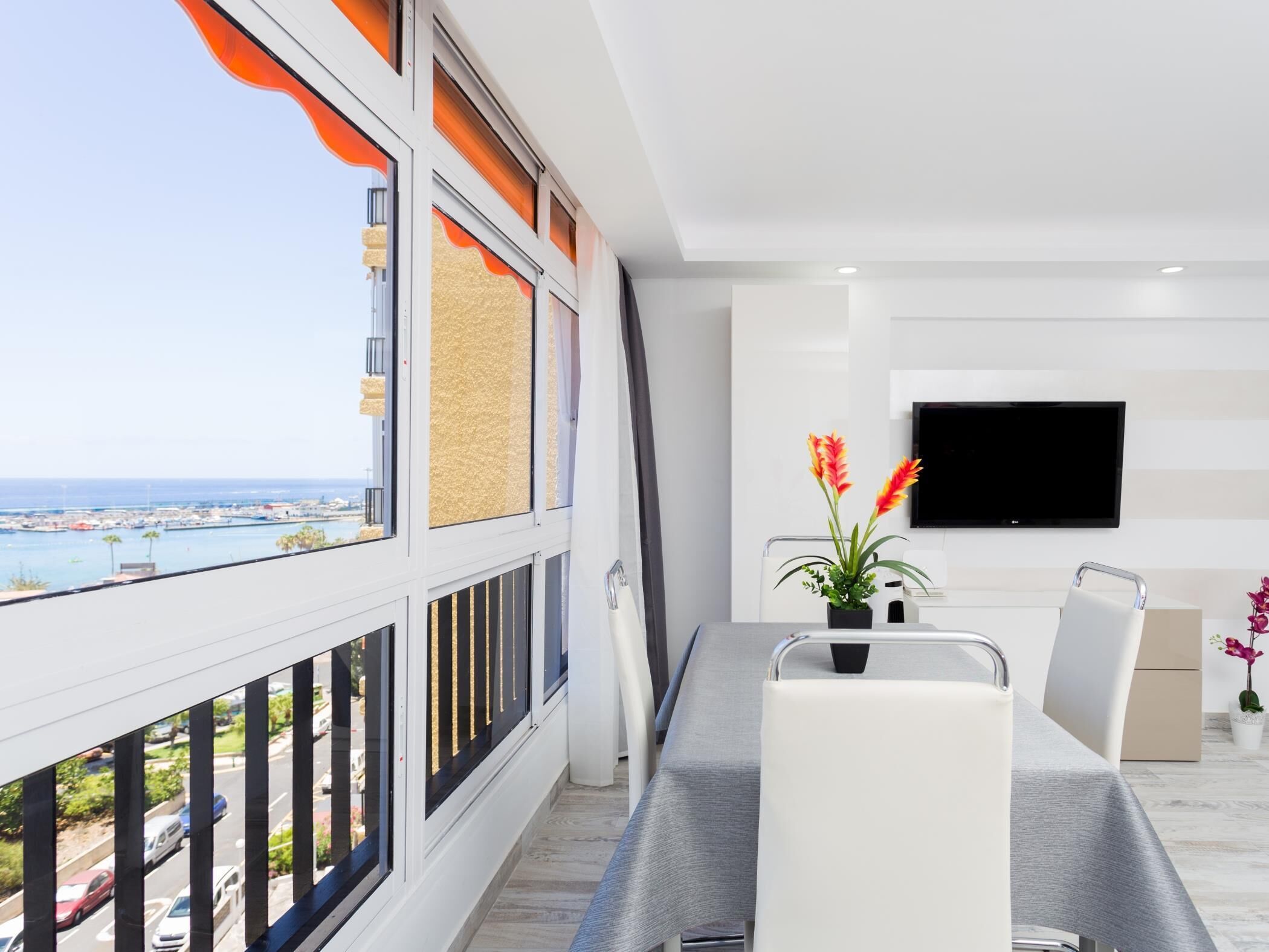 A modern living room with a balcony overlooking a marina.